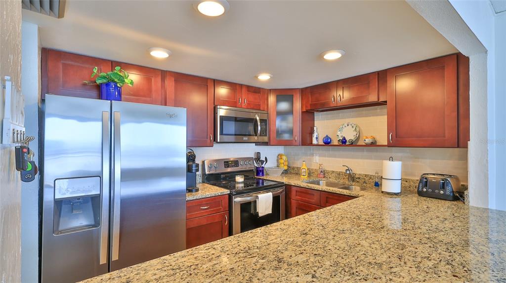 A kitchen with stainless steel appliances, dark wood cabinets, and granite countertops — 3051 S ATLANTIC AVENUE UNIT 2206, DAYTONA BEACH, FL