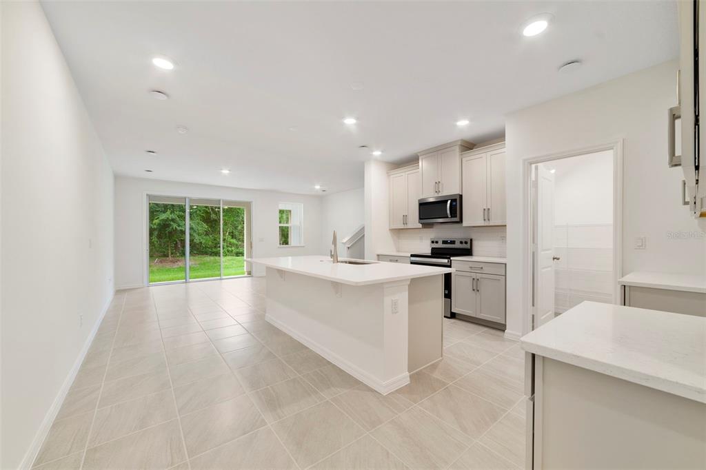 A modern kitchen features a white island, light-colored cabinetry, and tile flooring — 1665 GREENLEAF WOODS COVE, OVIEDO, FL