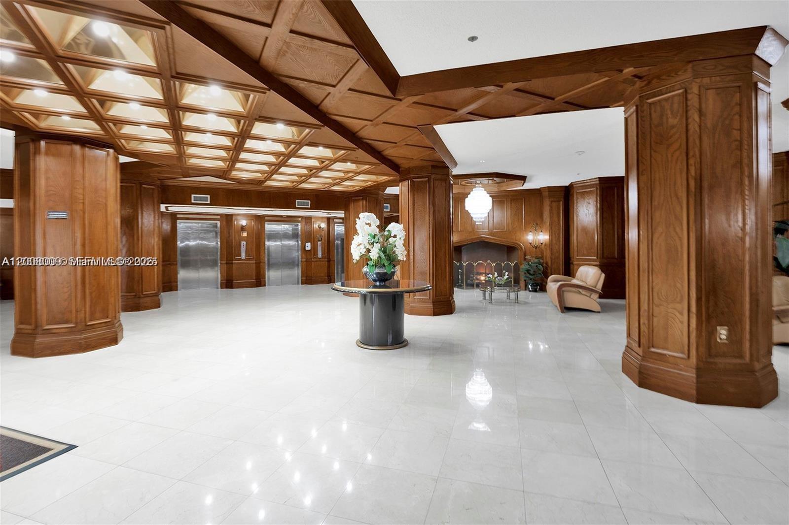 A lobby features wood-paneled walls, a coffered ceiling, marble floors, and a fireplace — 1865 S Ocean Dr # 12L, Hallandale Beach FL 33009, HALLANDALE BEACH, FL