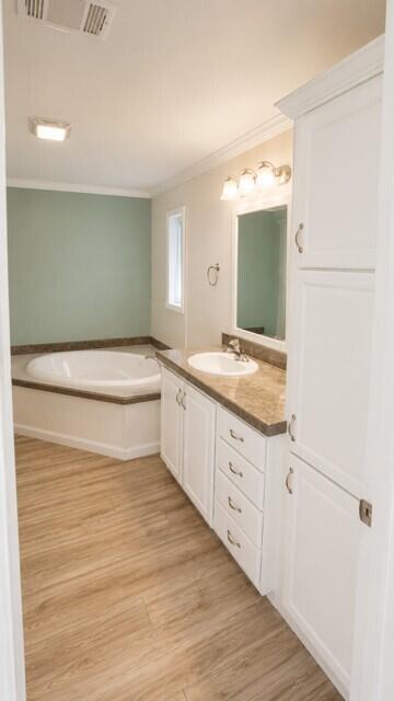 A bathroom features a white vanity, a corner soaking tub, and light wood-look flooring — 7079 SE Bluebird Circle, Hobe Sound FL 33455, HOBE SOUND, FL