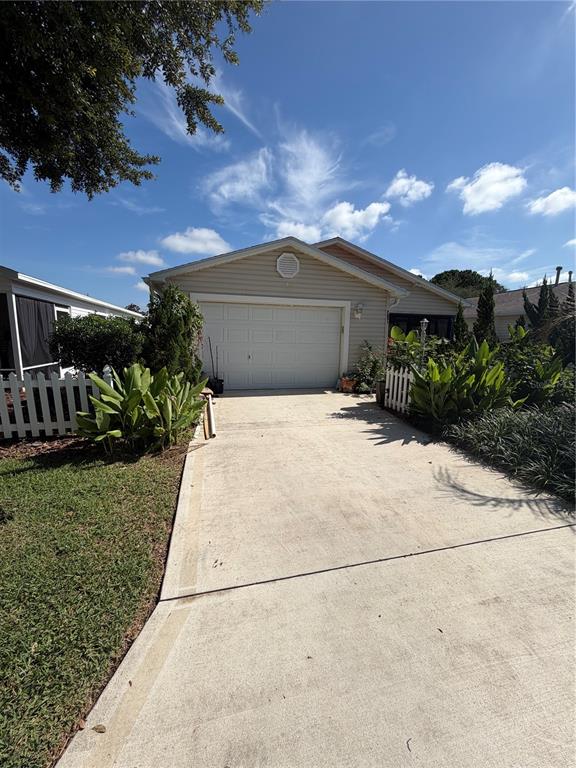 A beige house with a single-car garage and a concrete driveway under a blue sky — 7851 SE 173RD PANORAMA PLACE, THE VILLAGES, FL