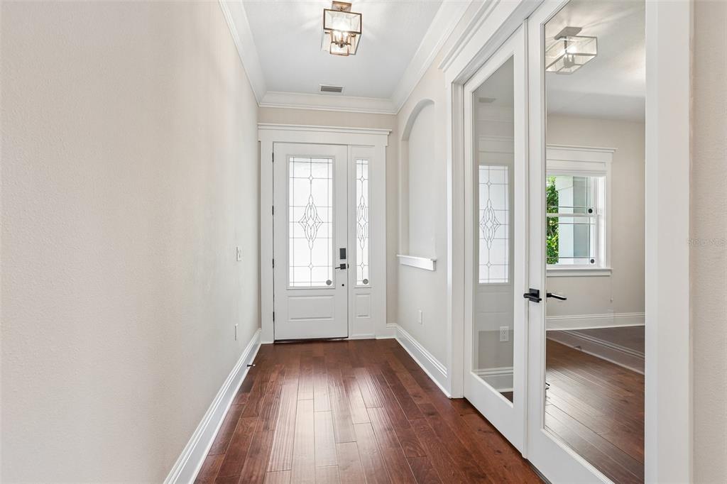 A bright entryway features hardwood floors, a white front door with glass, and French doors — 3627 E CLARK CIRCLE, TAMPA, FL