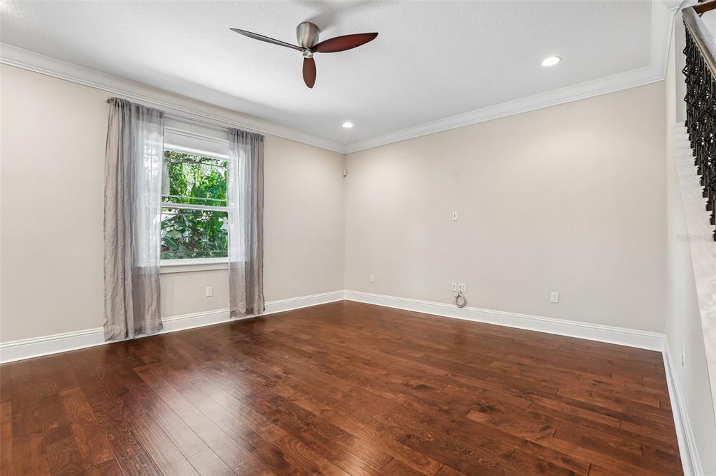 An empty room with hardwood floors, a ceiling fan, and a window with gray curtains — 3627 E CLARK CIRCLE, TAMPA, FL