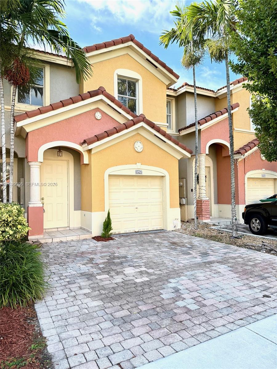 A two-story townhouse with a paved driveway, a single-car garage, and a tan stucco exterior — 8528 SW 166th Pl # 8528, Miami FL 33193, MIAMI, FL