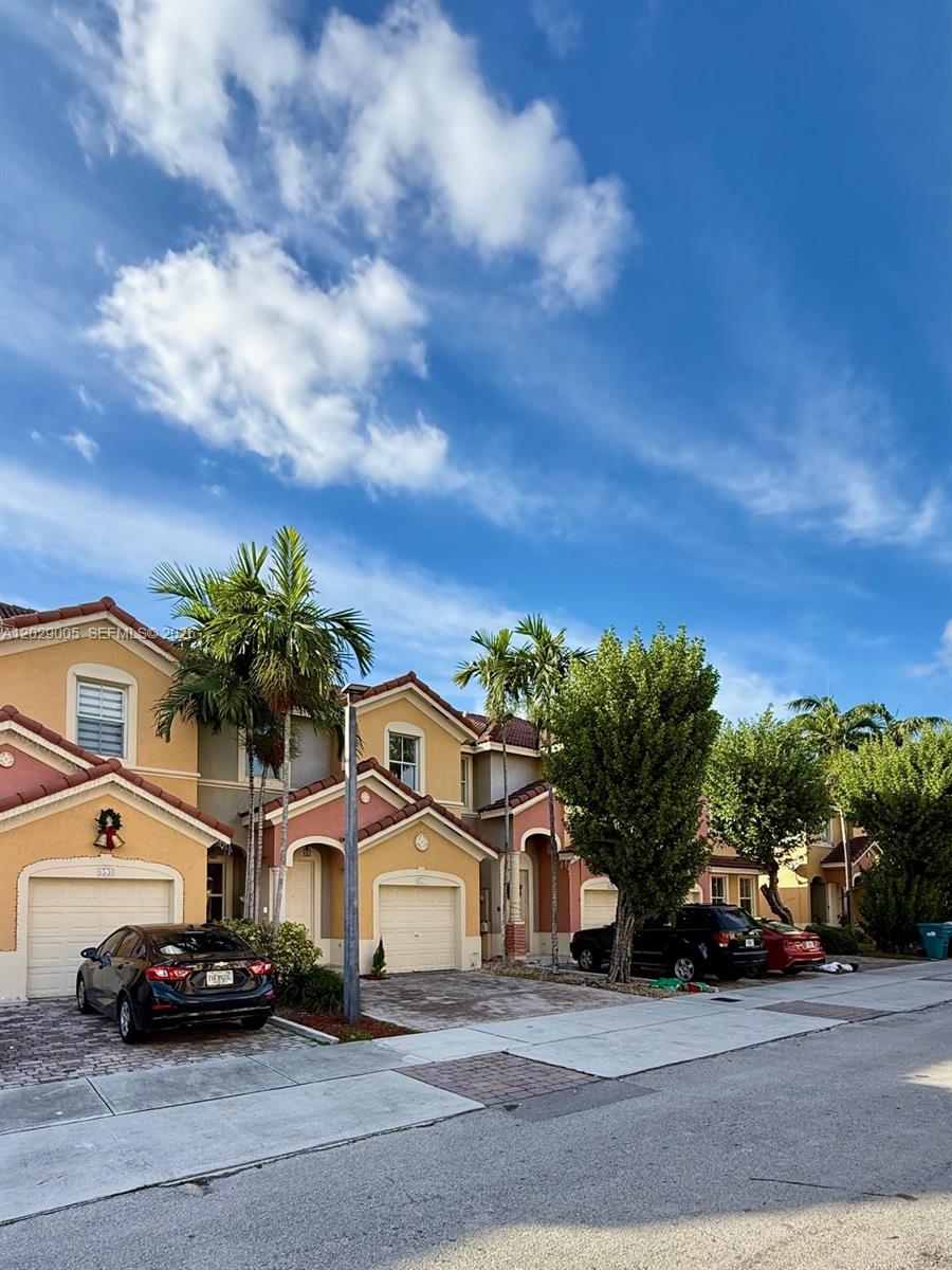 A row of two-story townhouses with beige and orange stucco exteriors and attached garages — 8528 SW 166th Pl # 8528, Miami FL 33193, MIAMI, FL
