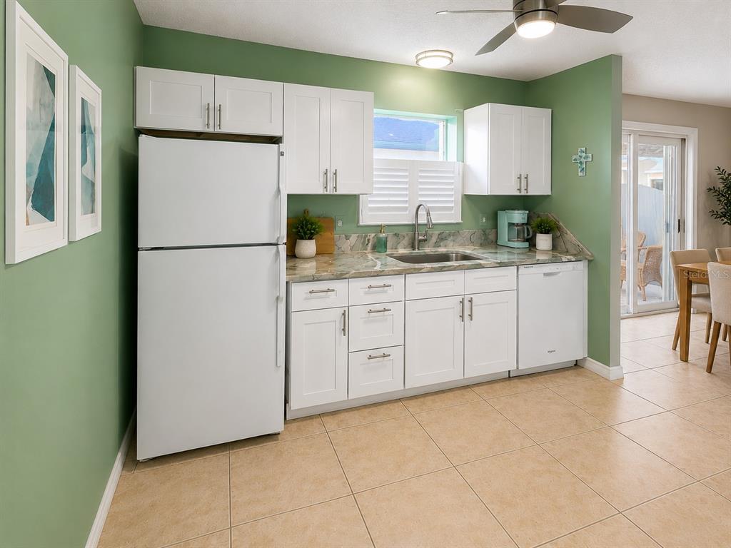 A kitchen features white cabinets, a white refrigerator, a stainless steel sink, and green walls — 408 DUARTE LANE, THE VILLAGES, FL