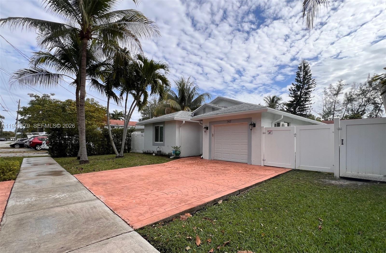 A single-story house with a white exterior, a red patterned driveway, and palm trees — 747 SW 6th St, Hallandale Beach FL 33009, HALLANDALE BEACH, FL
