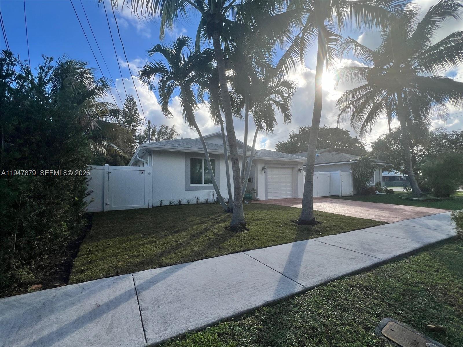 A single-story white house features a front lawn, palm trees, and a paved driveway — 747 SW 6th St, Hallandale Beach FL 33009, HALLANDALE BEACH, FL