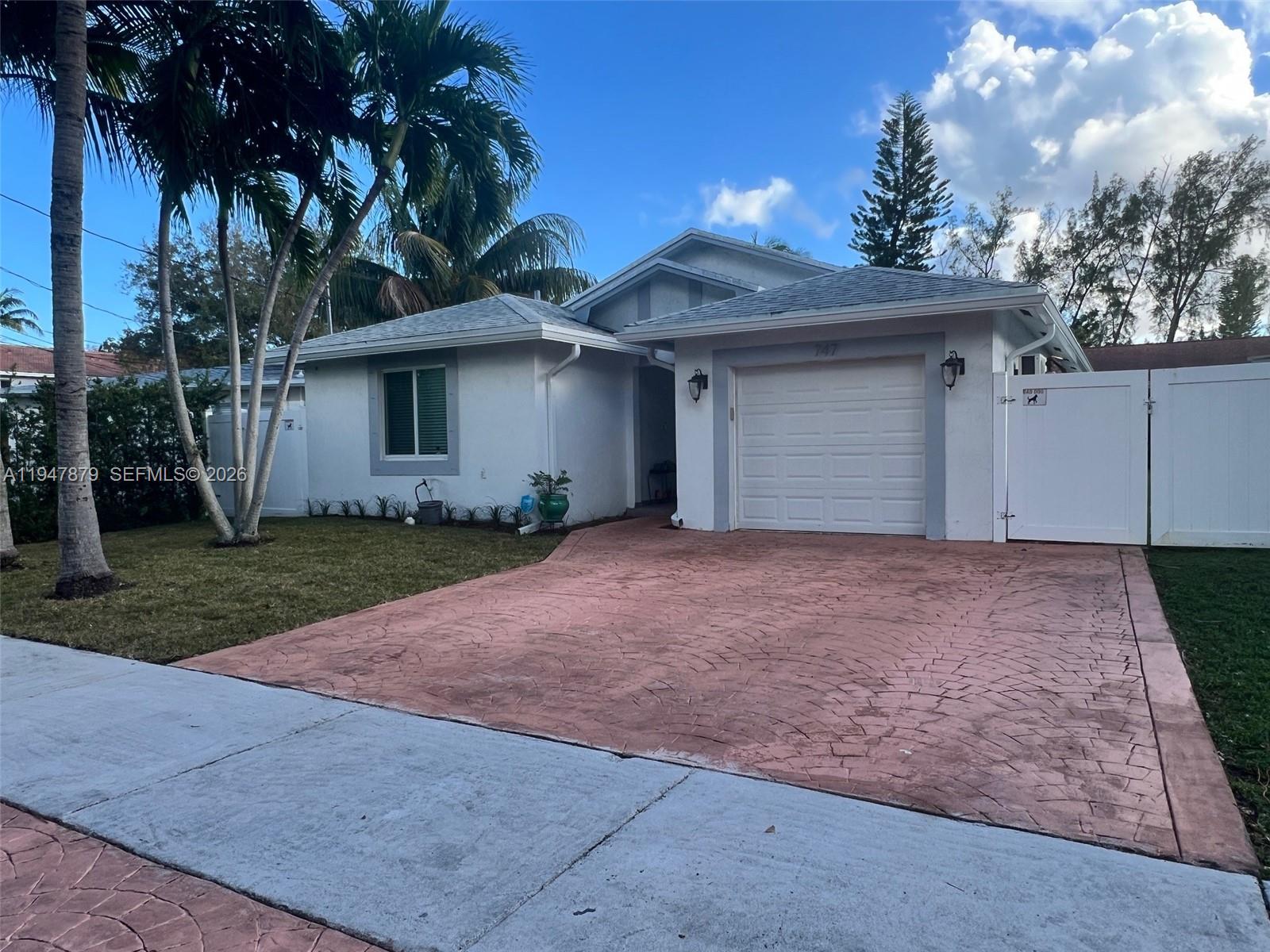 A white single-story house features a stamped concrete driveway and a white privacy fence — 747 SW 6th St, Hallandale Beach FL 33009, HALLANDALE BEACH, FL
