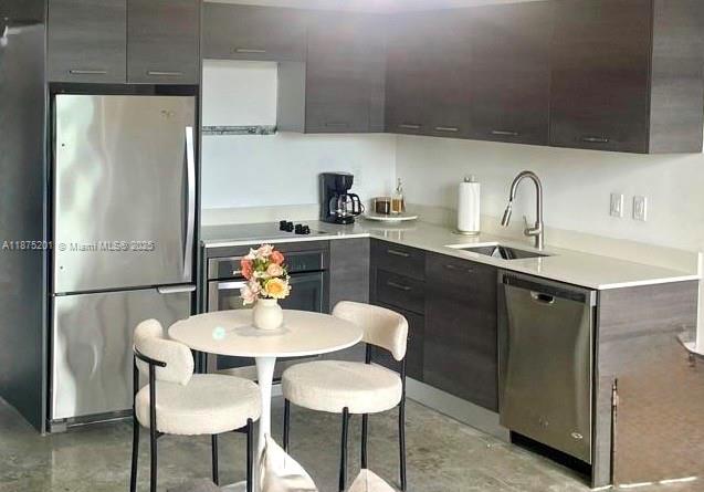 A modern kitchen features dark wood cabinetry, stainless steel appliances, and a small round dining table — 151 SE 1st St # 2807, Miami FL 33131, MIAMI, FL