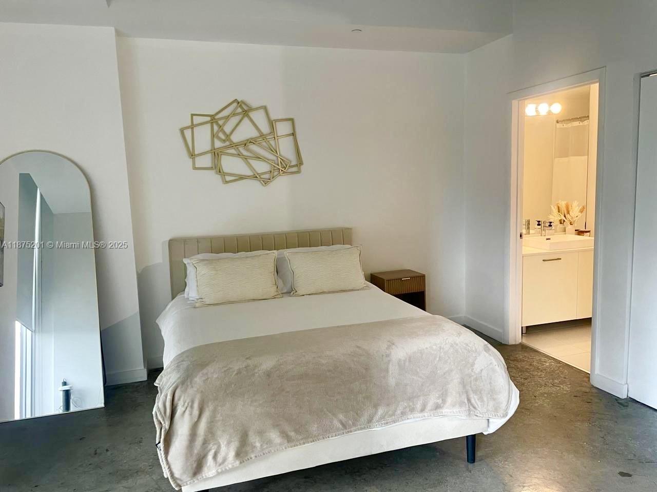 A bedroom features a bed with a beige headboard, a floor mirror, and an attached bathroom — 151 SE 1st St # 2807, Miami FL 33131, MIAMI, FL