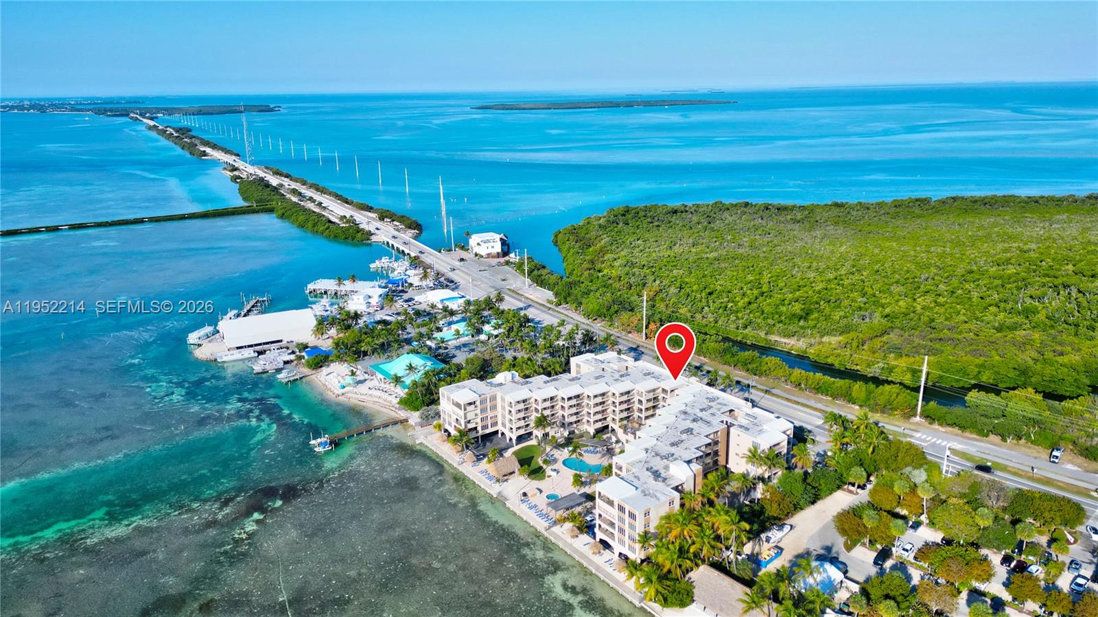 An aerial view shows a multi-story waterfront condominium complex located next to a highway bridge — 79901 Overseas Higway # 204, Islamorada FL 33036, ISLAMORADA, FL
