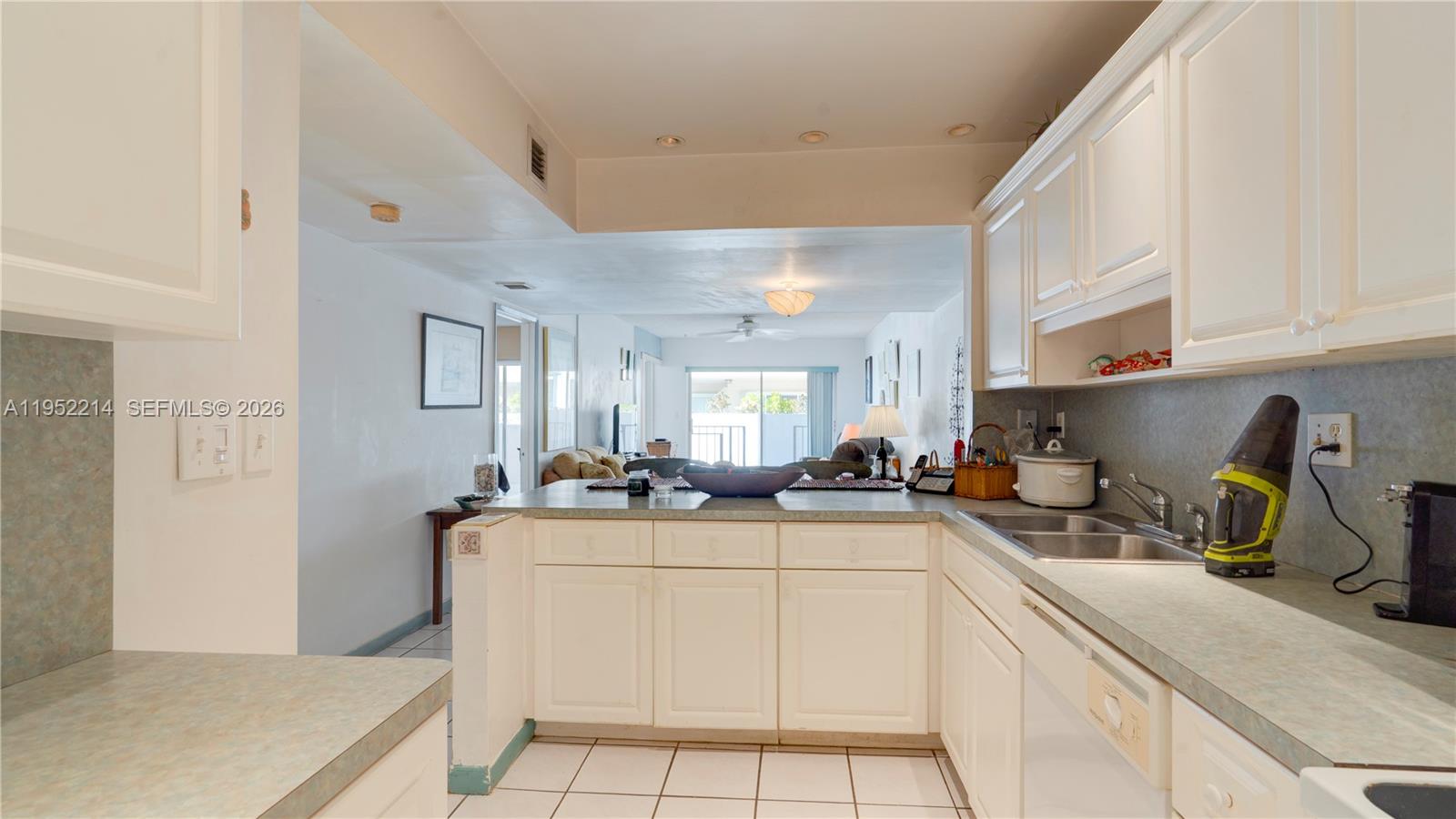 A kitchen with white cabinets and a breakfast bar overlooks a living area — 79901 Overseas Higway # 204, Islamorada FL 33036, ISLAMORADA, FL