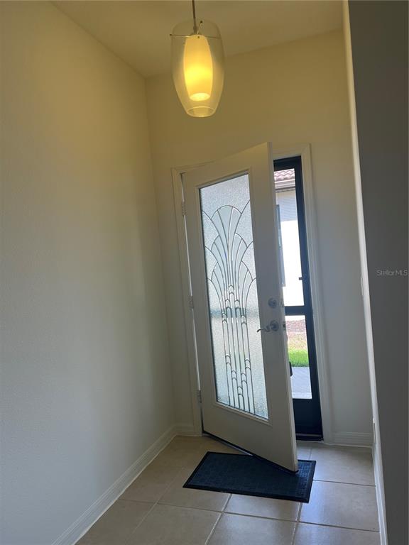An entryway features a tiled floor, a pendant light, and a white door with decorative glass — 1498 MASENO DRIVE, VENICE, FL