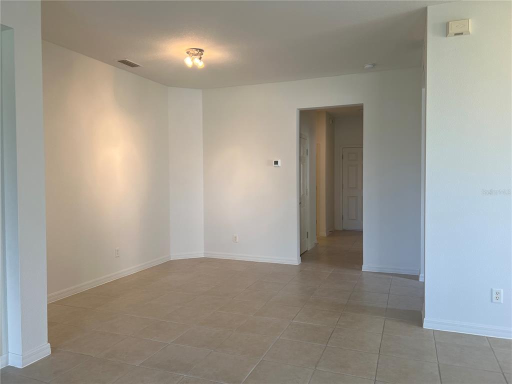 An empty room with light-colored tile flooring, white walls, and a ceiling light fixture — 1498 MASENO DRIVE, VENICE, FL