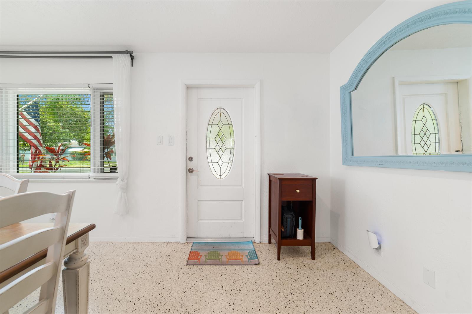 A white-walled entryway features a front door with an oval window, terrazzo flooring, and mirror — 245 SW 5th Street, Dania Beach FL 33004, DANIA BEACH, FL