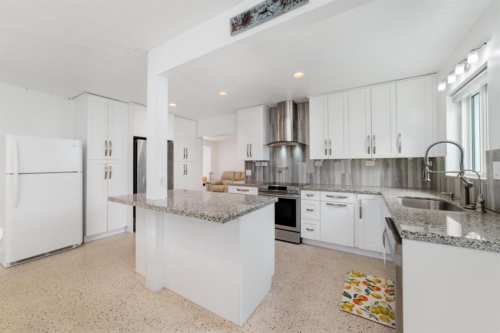 A kitchen features white cabinets, granite countertops, stainless steel appliances, and a speckled floor — 245 SW 5th Street, Dania Beach FL 33004, DANIA BEACH, FL