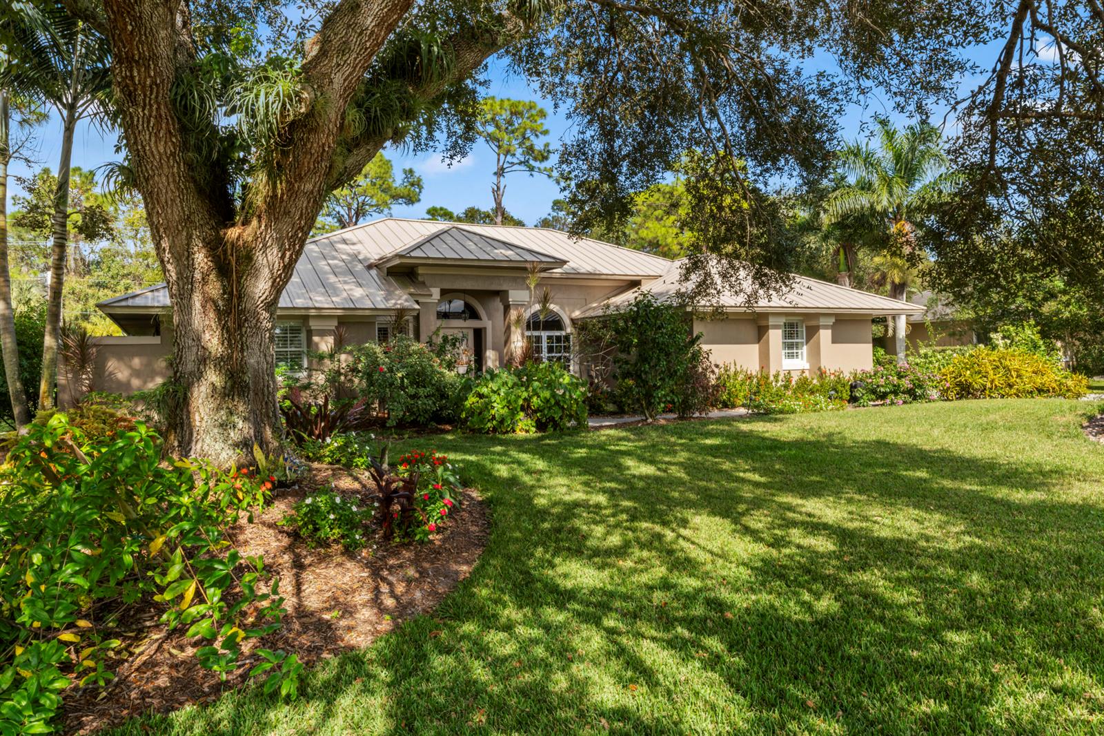 A single-story house with a metal roof sits behind a large tree and lawn — 3221 Bent Pine Drive, Fort Pierce FL 34951, FORT PIERCE, FL