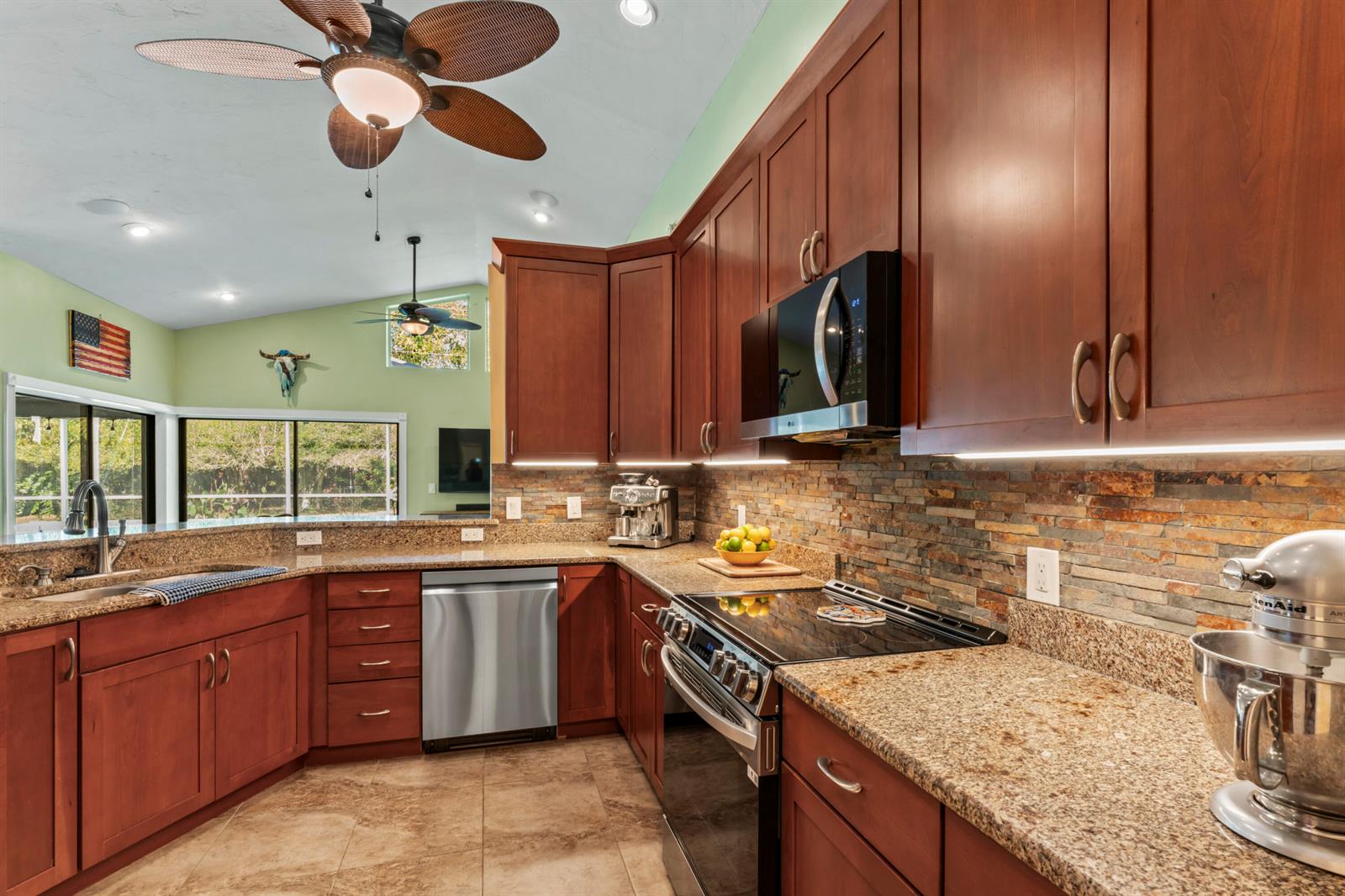 A kitchen features cherry wood cabinets, granite countertops, a stone backsplash, and stainless steel appliances — 3221 Bent Pine Drive, Fort Pierce FL 34951, FORT PIERCE, FL