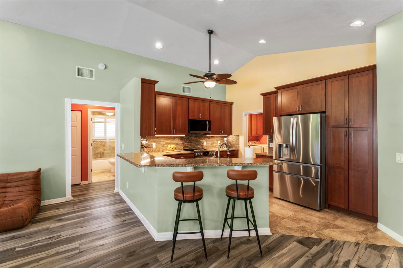A kitchen with wood cabinets, granite countertops, and a breakfast bar with two stools — 3221 Bent Pine Drive, Fort Pierce FL 34951, FORT PIERCE, FL