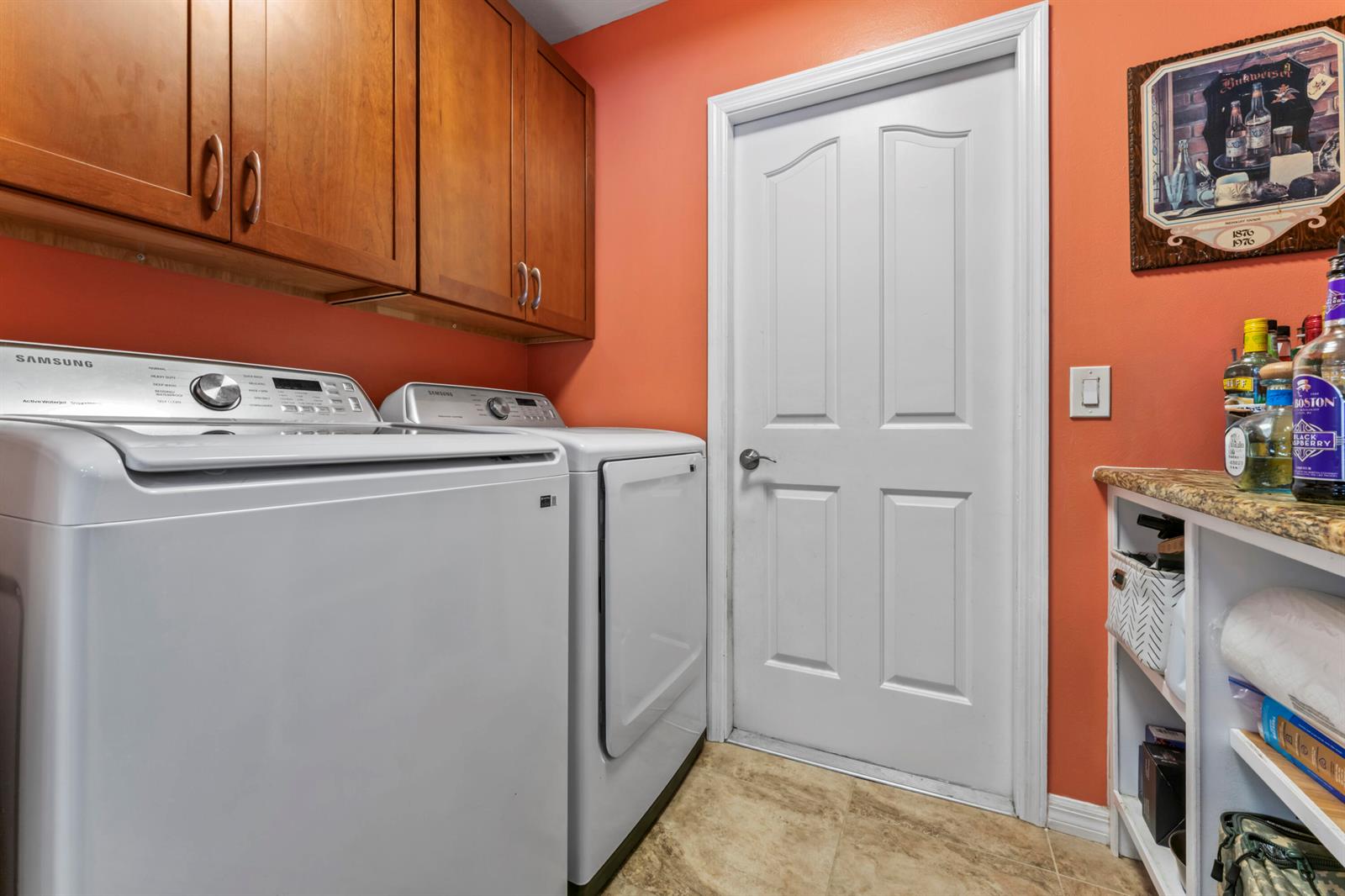 A laundry room features white appliances, wooden cabinets, orange walls, and a white door — 3221 Bent Pine Drive, Fort Pierce FL 34951, FORT PIERCE, FL