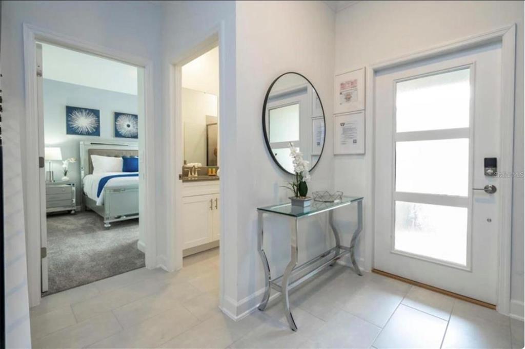 A bright entryway features a glass console table, oval mirror, and views into adjacent rooms — 2709 SCRAPBOOK STREET, KISSIMMEE, FL