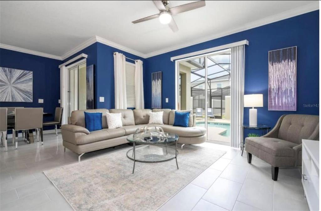A living room with blue walls, a beige sectional sofa, and a glass coffee table — 2709 SCRAPBOOK STREET, KISSIMMEE, FL