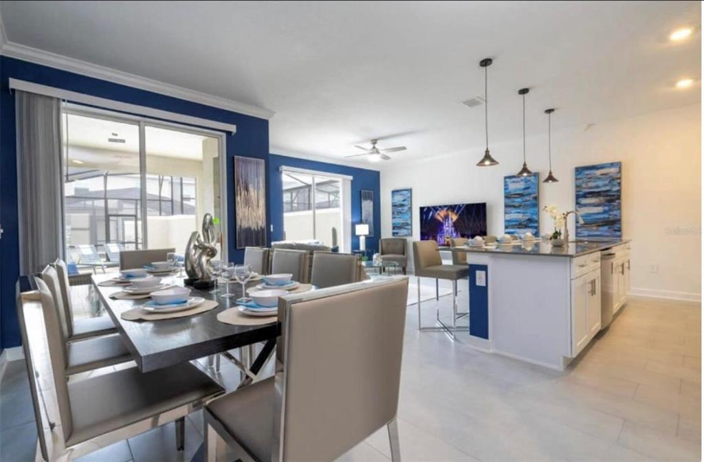 An open-concept dining area and kitchen feature a dark wood table, island seating, and blue walls — 2709 SCRAPBOOK STREET, KISSIMMEE, FL