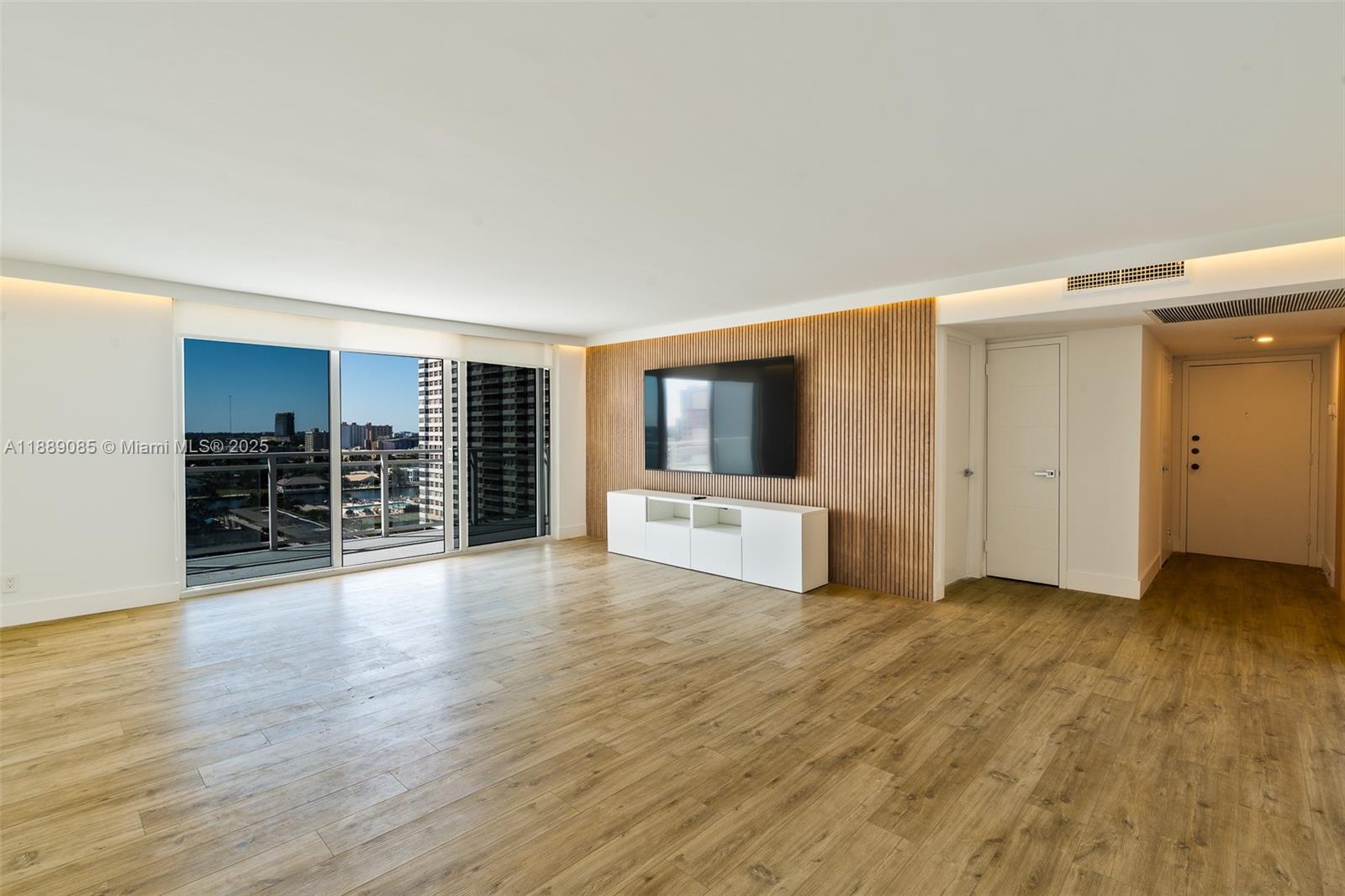 A living room features wood-look flooring, a slatted wood accent wall, and floor-to-ceiling windows — 2030 S Ocean Dr # 1127, Hallandale Beach FL 33009, HALLANDALE BEACH, FL