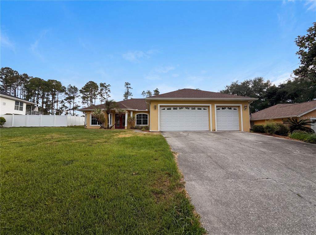 A single-story yellow house with a two-car garage and a concrete driveway — 10408 LAGO LOUISA COURT, CLERMONT, FL