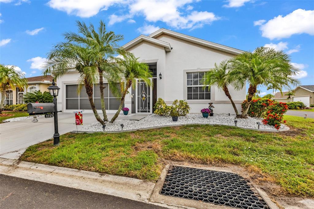 A single-story house with a white stucco exterior, palm trees, and a landscaped front yard — 1725 PICCADILLY CIRCLE, PUNTA GORDA, FL