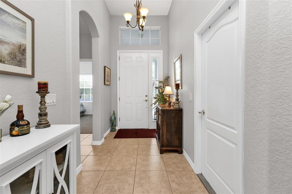 An entryway with tiled floors, a white front door, and a wooden console table — 1725 PICCADILLY CIRCLE, PUNTA GORDA, FL