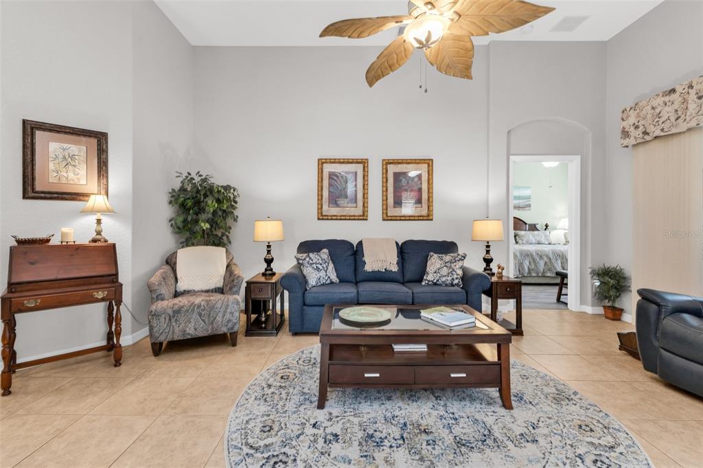 A living room features a blue sofa, a round rug, and a palm-leaf ceiling fan — 1725 PICCADILLY CIRCLE, PUNTA GORDA, FL