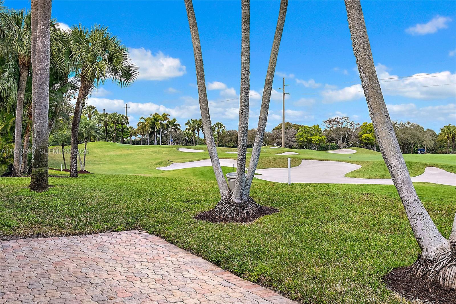 A view of a golf course with sand bunkers, palm trees, and a brick patio — 108 Waters Edge Dr, Jupiter FL 33477, JUPITER, FL