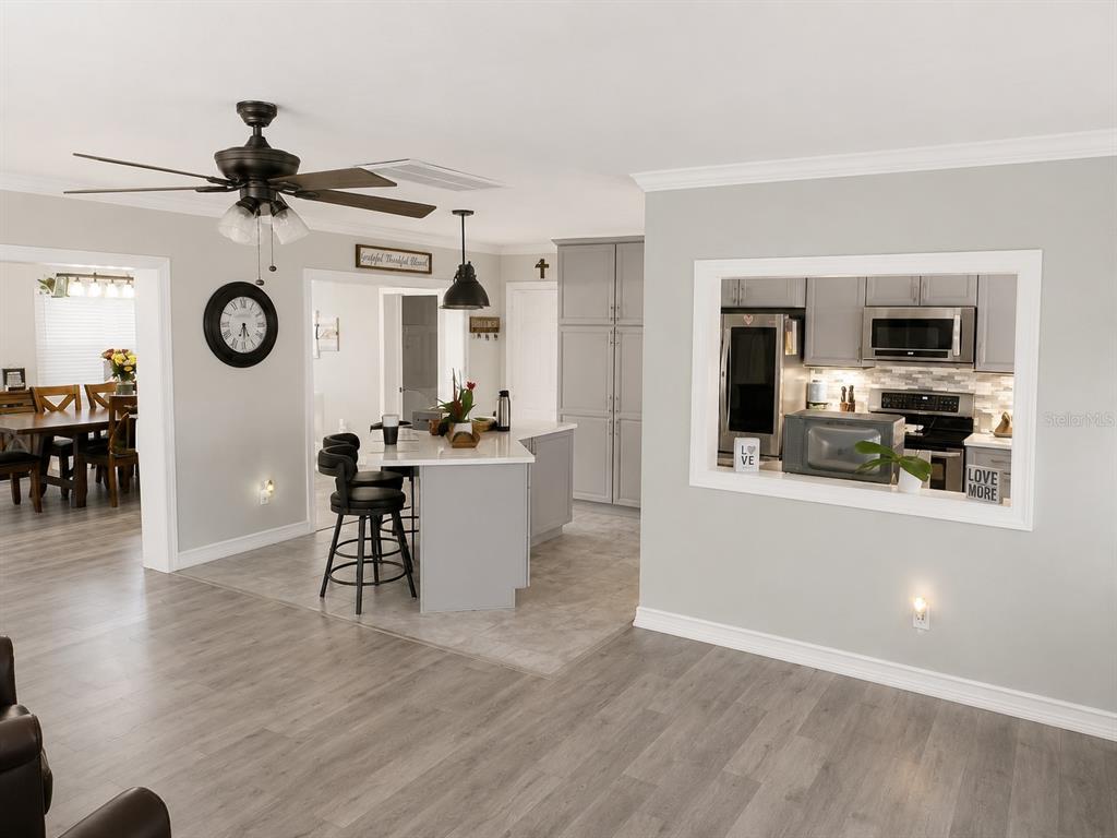 A view of a kitchen with a pass-through window, island, and adjacent dining area — 2001 MAGNOLIA DRIVE, CLEARWATER, FL