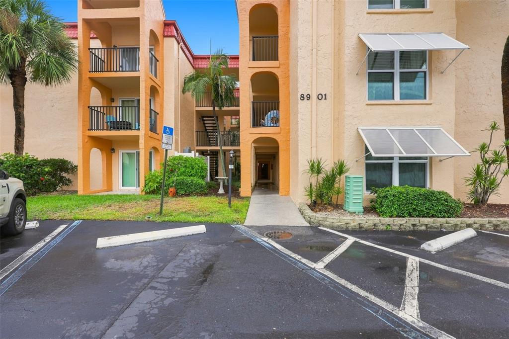 The exterior of a multi-story apartment building features balconies, a walkway, and a parking lot — 8901 BLIND PASS ROAD UNIT 232, ST PETE BEACH, FL