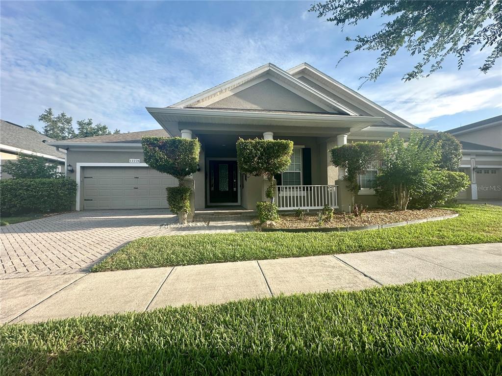A single-story house with a gray exterior, a paved driveway, and a covered front porch — 13226 ZORI LANE, WINDERMERE, FL