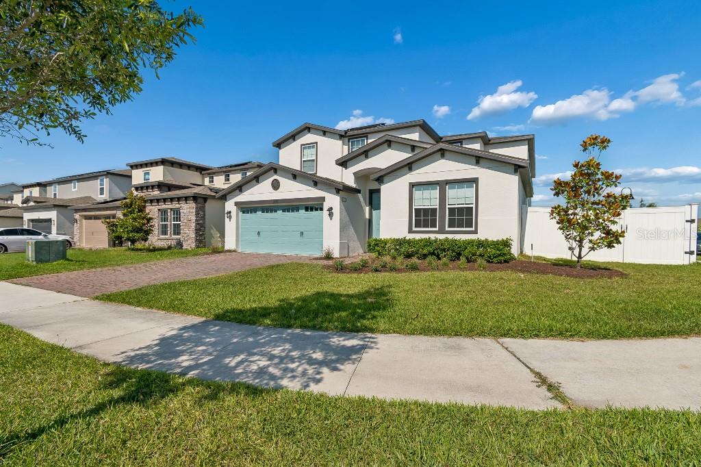 A two-story suburban house with a light-colored exterior, a blue garage door, and a lawn — 1101 LONE PALM WAY, ST CLOUD, FL