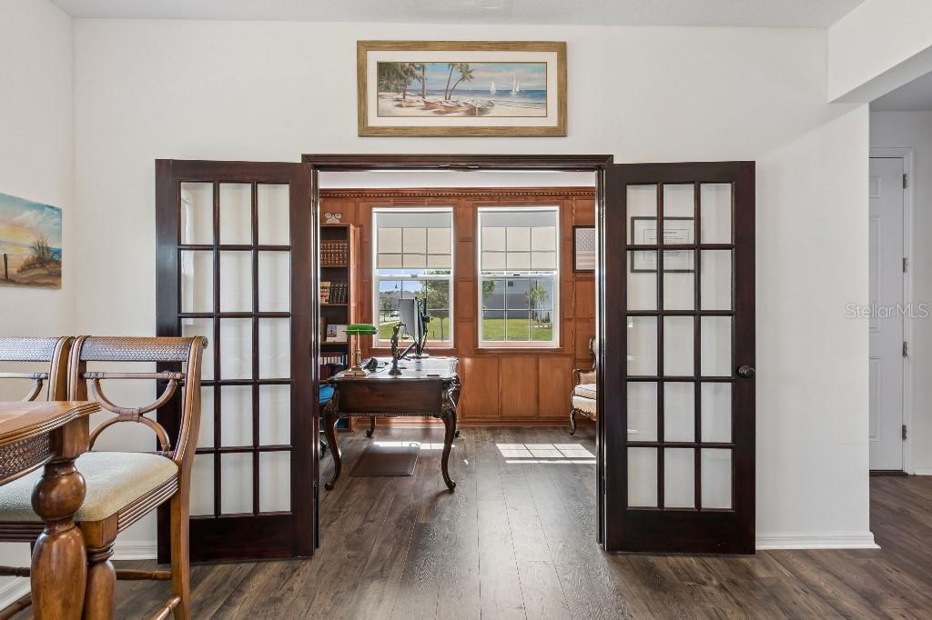 A home office with wood paneling and a desk is visible through open French doors — 1101 LONE PALM WAY, ST CLOUD, FL