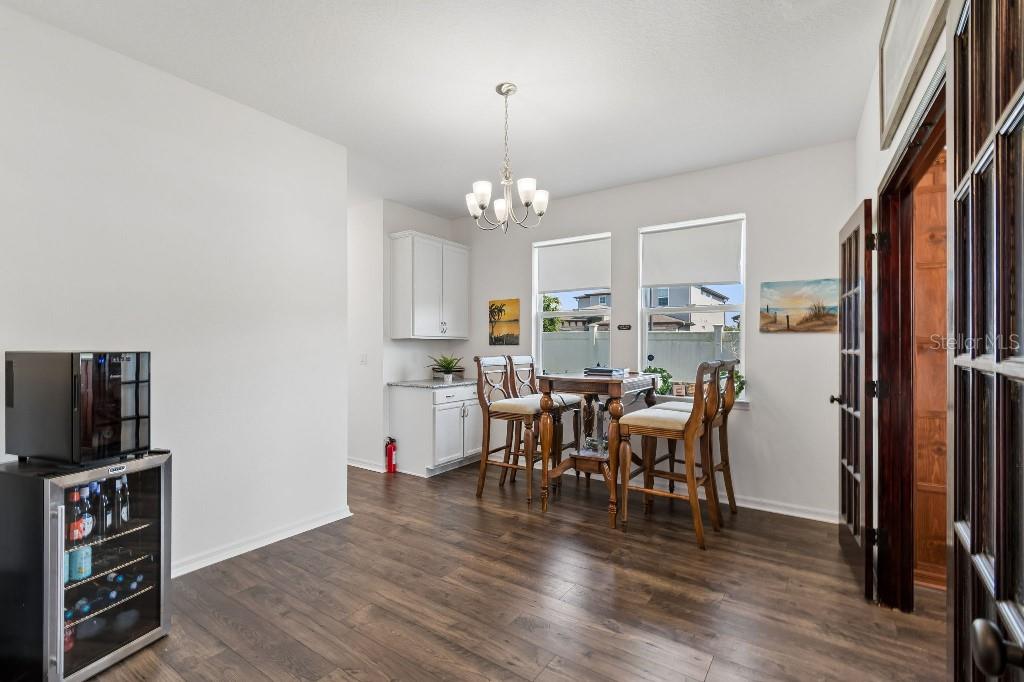 A dining area features wood-look flooring, a chandelier, a small bar cabinet, and a table — 1101 LONE PALM WAY, ST CLOUD, FL