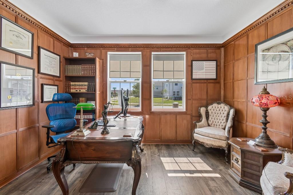 A home office features wood-paneled walls, a large wooden desk, and two windows — 1101 LONE PALM WAY, ST CLOUD, FL
