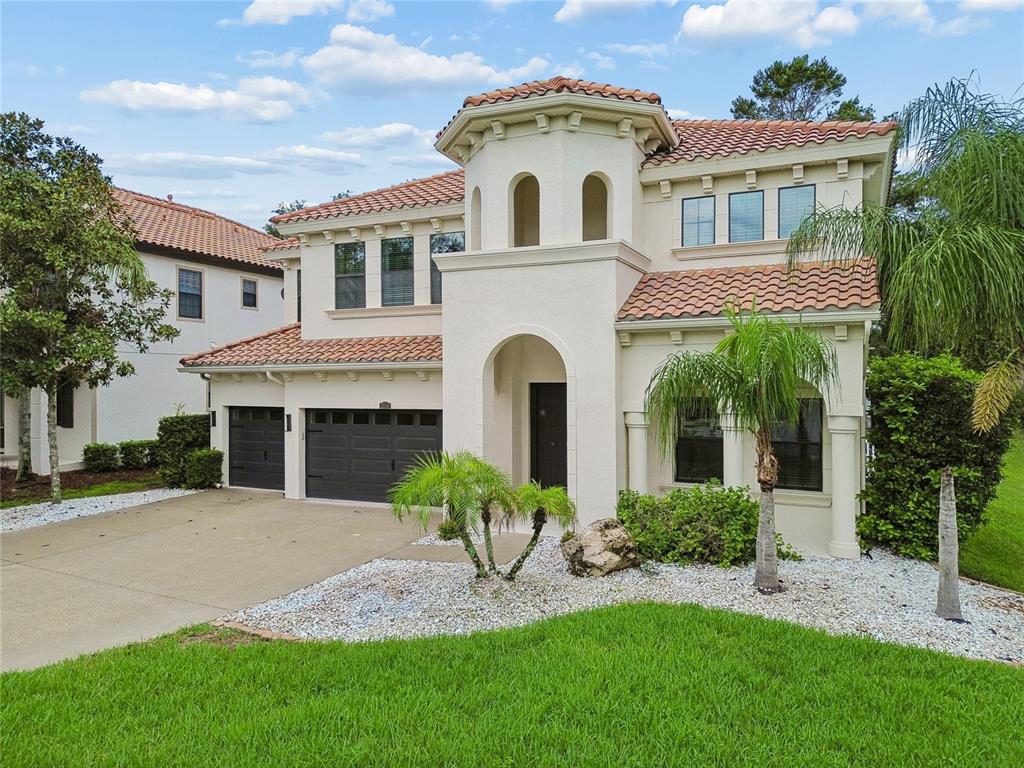 A two-story Mediterranean-style house with a stucco exterior, tile roof, and a three-car garage — 2719 CALVANO DRIVE, LAND O LAKES, FL