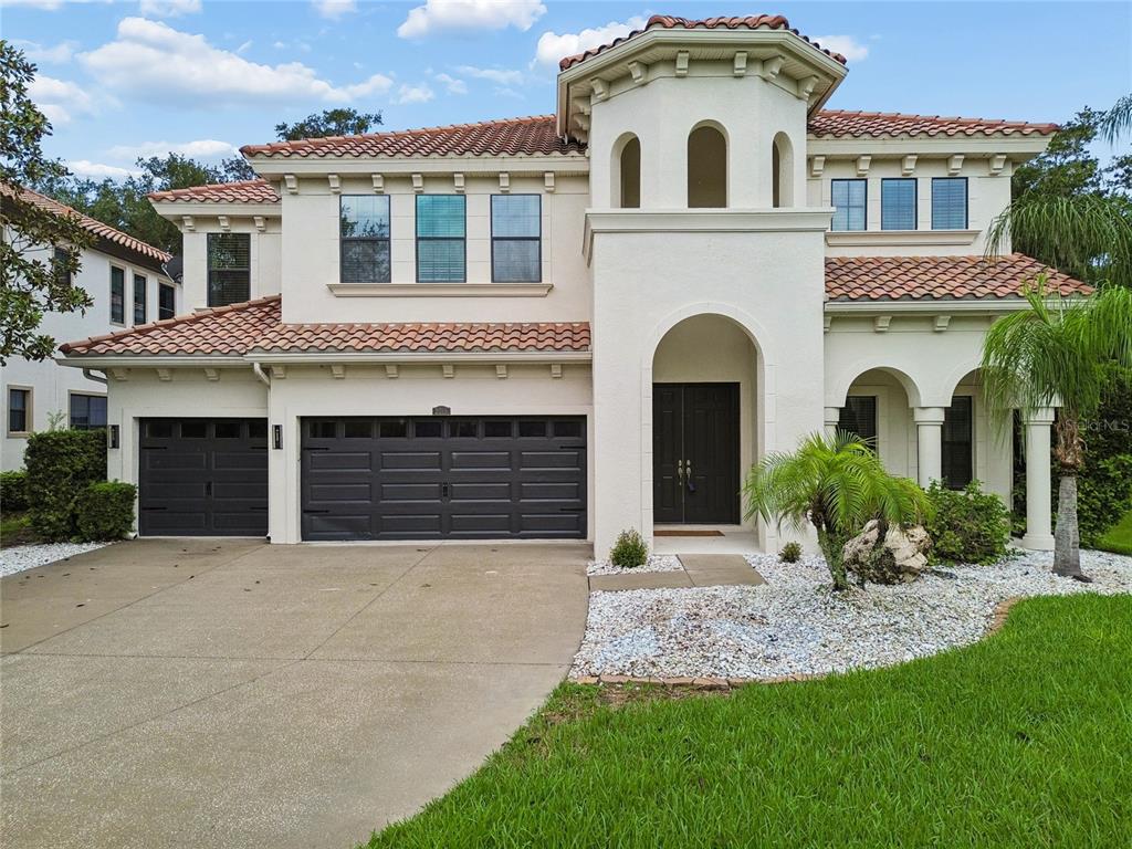 A two-story Mediterranean-style house with a tile roof, stucco exterior, and a three-car garage — 2719 CALVANO DRIVE, LAND O LAKES, FL