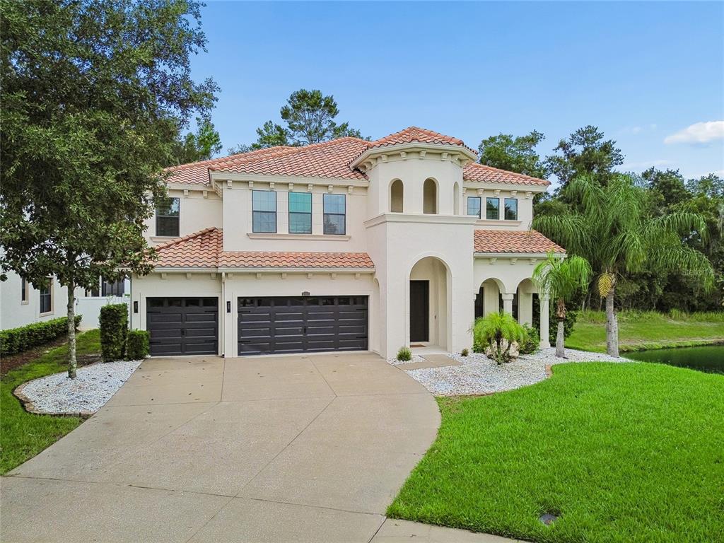 A two-story Mediterranean-style house with a tile roof, three-car garage, and a concrete driveway — 2719 CALVANO DRIVE, LAND O LAKES, FL