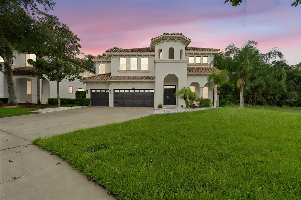 A two-story Mediterranean-style house with a tile roof, three-car garage, and a concrete driveway — 2719 CALVANO DRIVE, LAND O LAKES, FL
