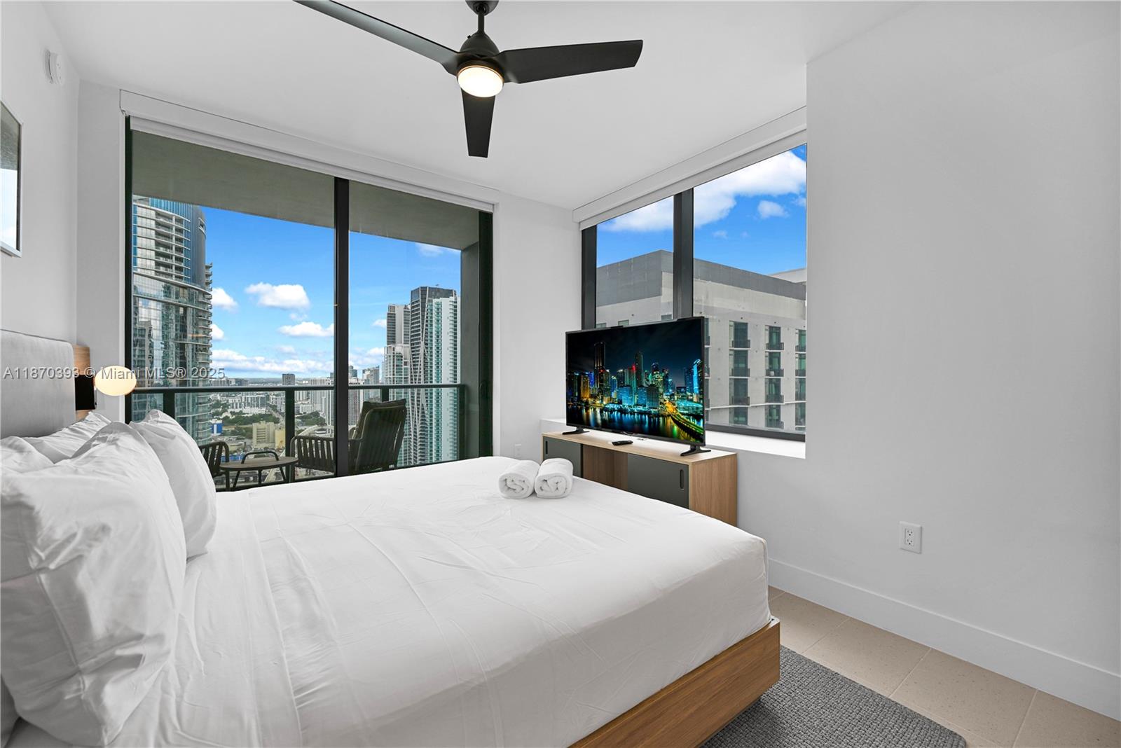 A bedroom features a bed, a television on a console, and floor-to-ceiling windows with city views — 159 NE 6th St # 3901, Miami FL 33132, MIAMI, FL