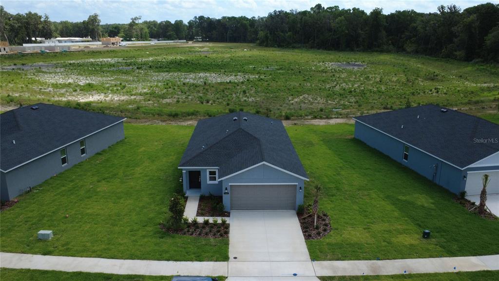 An aerial view shows a single-story house with a garage and lawn facing an open field — 1481 NW 48TH TER, OCALA, FL