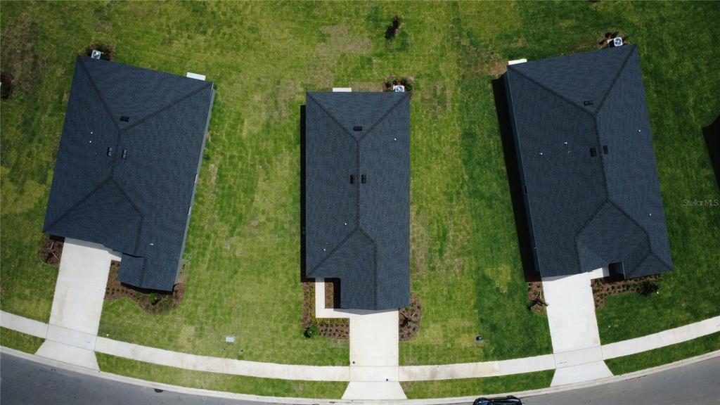 An aerial view shows three detached houses with dark shingled roofs and concrete driveways — 1481 NW 48TH TER, OCALA, FL
