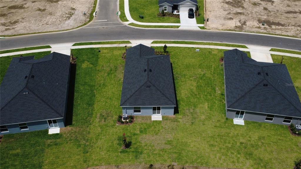 An aerial view shows the backyards and rear exteriors of three suburban single-family homes — 1481 NW 48TH TER, OCALA, FL