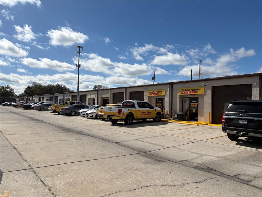 A row of commercial warehouse units with parked vehicles in a paved parking lot — 9212 LAZY LANE, TAMPA, FL